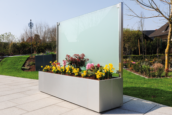 Mit satiniertem Glas dient die Glaswand sowohl als Windschutz als auch als Sichtschutz für elegante Privatsphäre im Garten