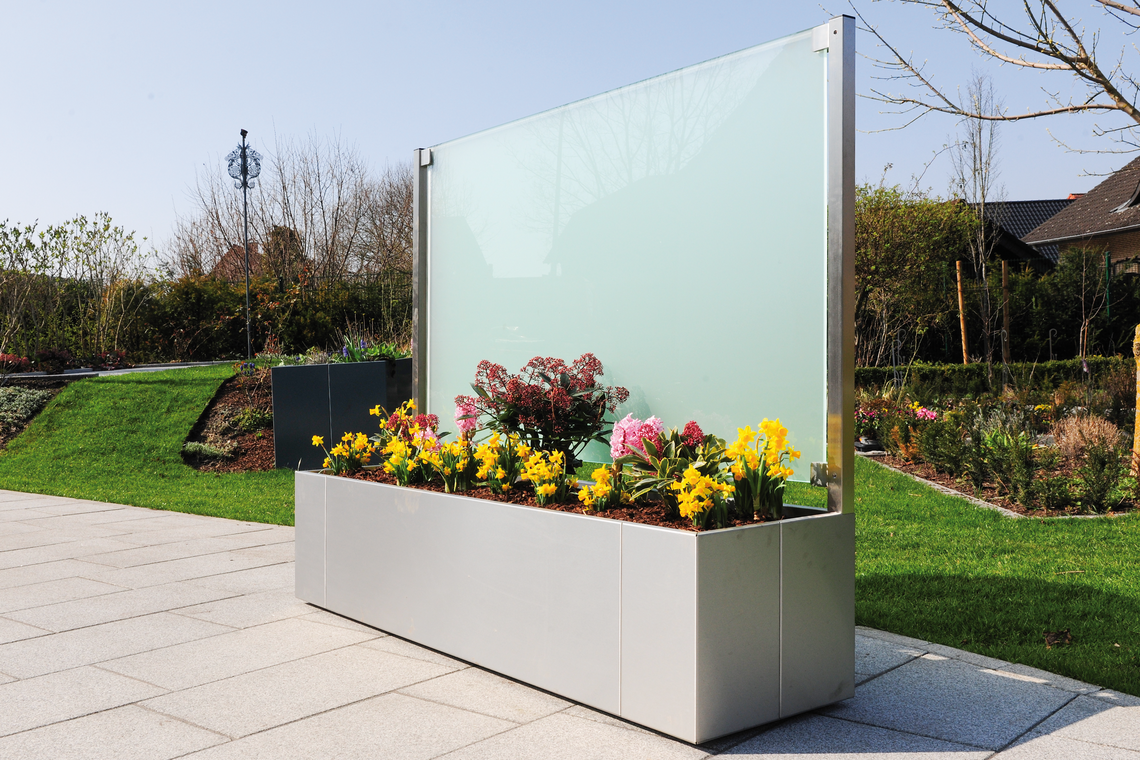 Mit satiniertem Glas dient die Glaswand sowohl als Windschutz als auch als Sichtschutz für elegante Privatsphäre im Garten